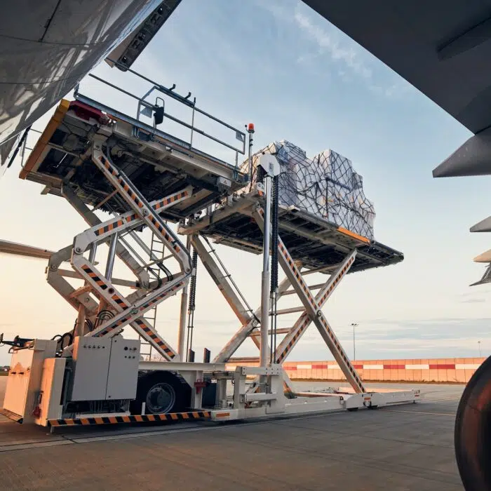 Loading of cargo containers to airplane at sunset